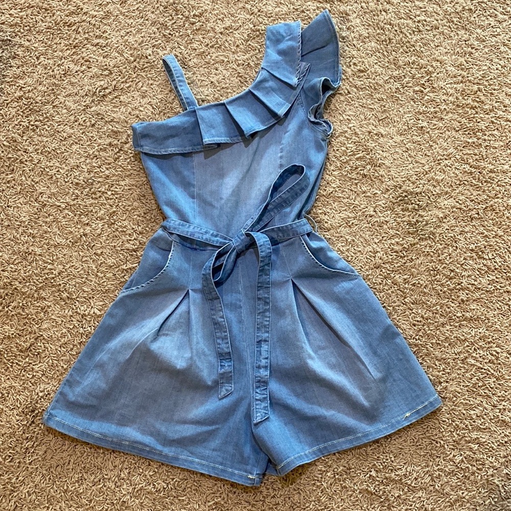 Habitual light denim romper. Asymmetric shoulder w/ ruffle. Pockets & belt